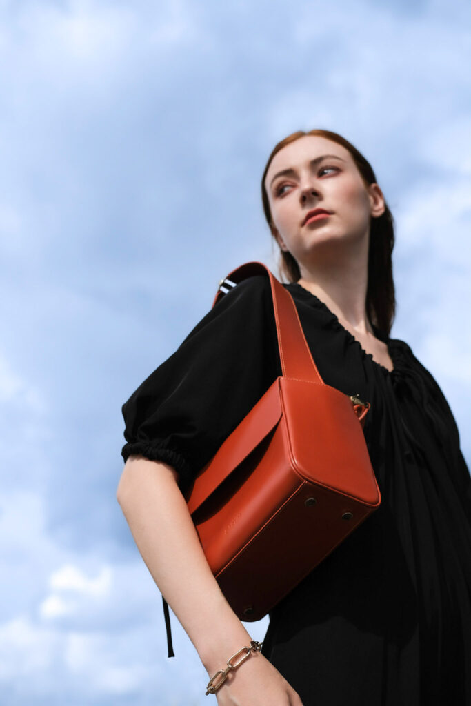 Bartin's Bozo23 premium leather bag held as handbag by woman in black dress.