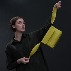 woman holding yellow leather handbag by shoulder straps