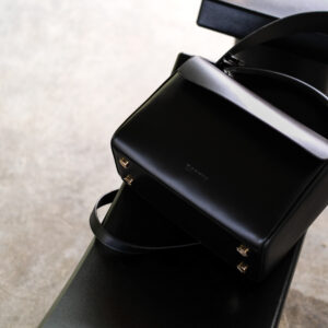 black leather handbag on its side with long shadow