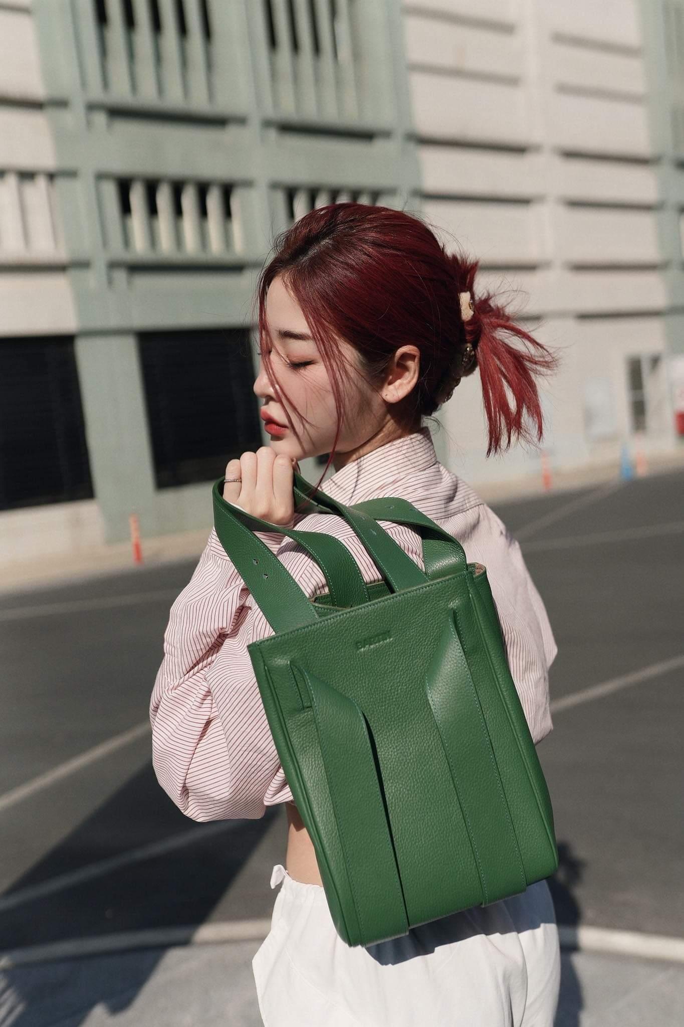 woman holding a green leather shoulder bag while standing in street in singapore